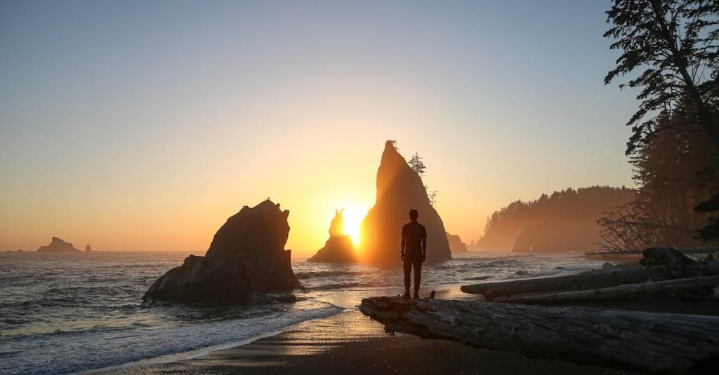 Dramatic sea stacks rise from the waves at Rialto Beach in Olympic National Park during golden hour sunset.